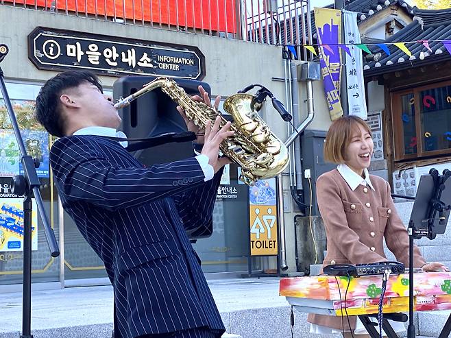 Jazz duo Grooveus, composed of saxophonist Han Hun-sik (left) and keyboardist Park Ji-yun, performs "September" by Earth, Wind and Fire at the Donuimun Musuem Village in central Seoul on Tuesday. (Hwang Joo-young/The Korea Herald)