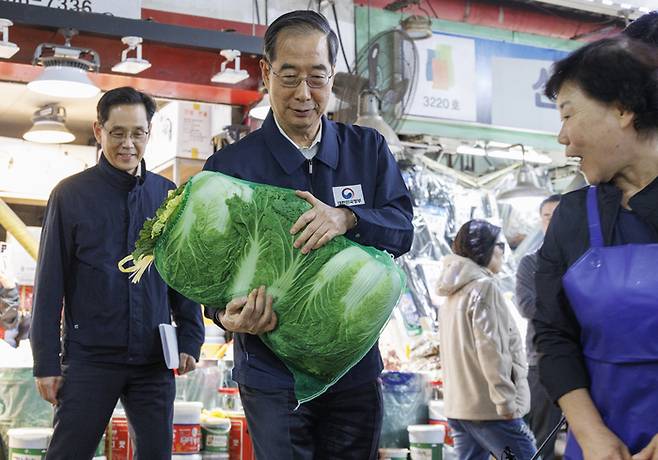 한덕수 국무총리가 지난달 24일 서울 마포구 마포농수산물시장을 방문해 직접 배추를 골라 구입하고 있다. 연합뉴스