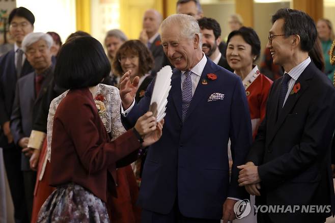 부채를 펴보라고 권유받는 영국 찰스 3세 국왕 (AP=연합뉴스) 영국 찰스 3세 국왕이 8일(현지시간) 뉴몰든 한인타운을 방문해서 한인들과 만났다. 찰스 3세는 부채를 펴보라는 권유를 받고 시도해봤으나 잘되지 않자 껄껄 웃었다. 2023.11.8 photo@yna.co.kr