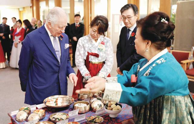 찰스 3세 영국 국왕이 8일(현지시간) 런던 뉴몰든 한인타운의 감리교회를 찾아 교민들이 국왕의 75세 생일을 축하하기 위해 마련한 한식 생일상을 살펴보며 이야기를 나누고 있다. 로이터연합뉴스