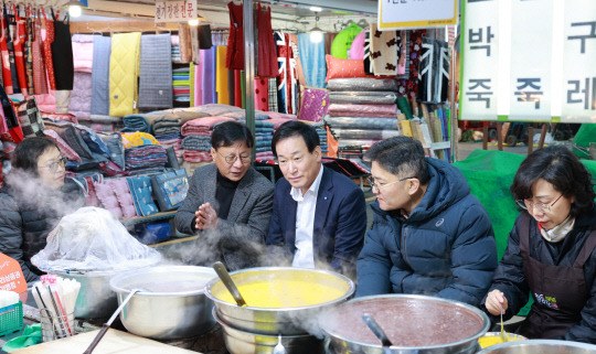 박완식 우리카드 대표이사 사장(왼쪽 세 번째)이 13일 서울 영등포전통시장을 직접 방문해 김태원 상인회장(왼쪽 두 번째) 및 상인들과 호박죽을 먹으며 대화하고 있다. [사진=우리카드]