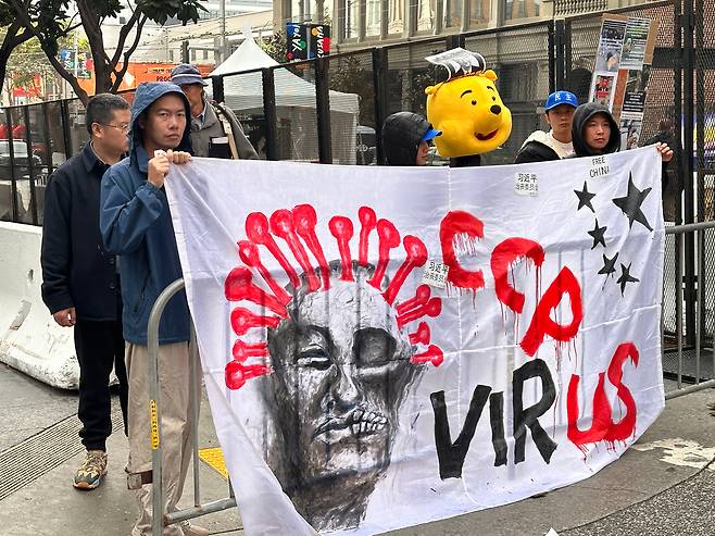 15일(현지 시각) APEC이 열린 미국 샌프란시스코에서 반중 시위대가 시진핑 중국 국가주석을 희화화하는 위니 더 푸 인형과 'CCP(중국 공산당) 바이러스'라고 쓰여진 천을 흔들고 있다. /샌프란시스코=오로라 특파원