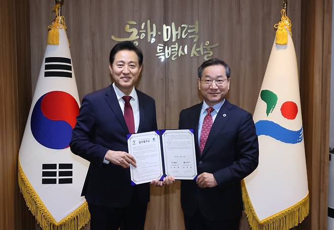 Seoul Mayor Oh Se-hoon (left) and Incheon Mayor Yoo Jeong-bok (right) pose for a picture at Seoul City Hall after signing the new public transportation policy agreement, Friday. (Yonhap)