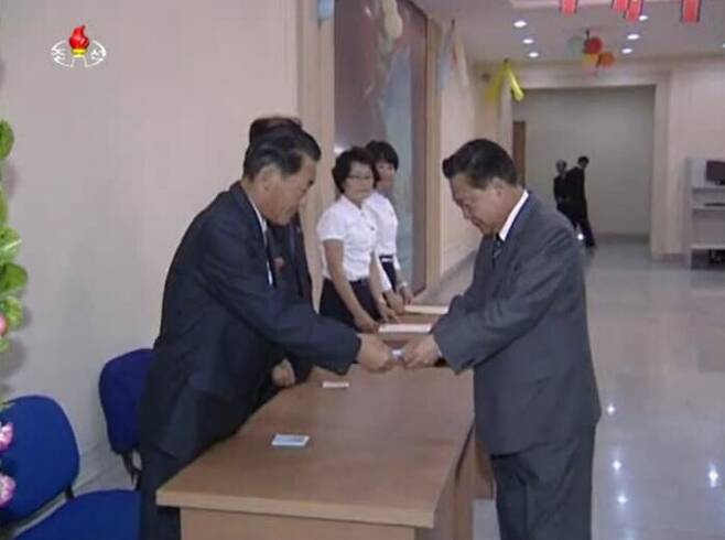 투표자가 선거장에서 '선거표'를 교부받는 모습 (조선중앙TV, 2015년 7월)