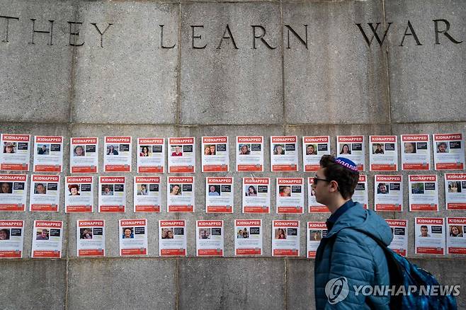 뉴욕 유엔 본부 밖에 붙은 하마스 인질 사진 (뉴욕 AFP·게티이미지=연합뉴스) 24일(현지시간) 유엔 안전보장이사회(안보리) 회의를 앞두고 뉴욕 유엔본부 밖에 붙은 하마스 인질 사진 앞을 한 남성이 지나가고 있다. 팔레스타인 무장 정파 하마스는 지난 7일 이스라엘을 기습 공격해 민간인을 살해하고 인질 삼았다. 2023.10.25 besthope@yna.co.kr