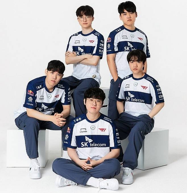 2023 LoL 월드 챔피언십 우승팀 T1 소속 선수들이 SK텔레콤, 메르세데츠 벤츠 등 후원사가 적힌 옷을 입고 포즈를 취하고 있다. 메르세데츠 벤츠