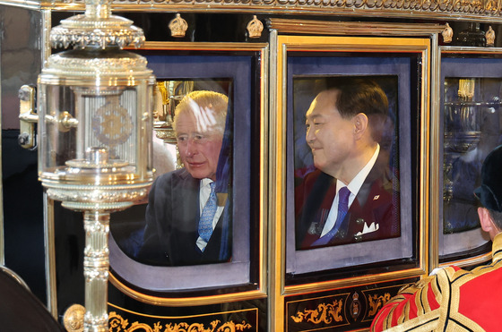 Korean President Yoon Suk Yeol, right, and King Charles III speak as they leave by carriage following a welcome ceremony at Horse Guards Parade for Buckingham Palace in London Tuesday. [JOINT PRESS CORPS]