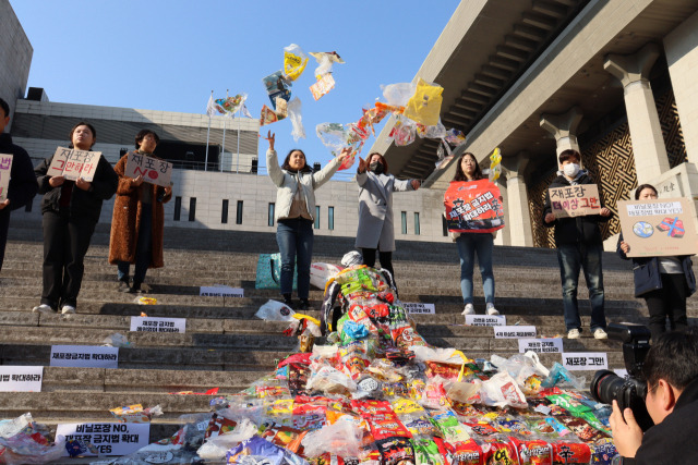 ? 꽃도안녕 팀과 서울환경연합 등 관계자들이 22일 세종문화회관 앞에서 퍼포먼스를 진행하고 있다. 재포장 금지법 규제 대상에서 제외된 재포장 비닐이 포장 쓰레기 문제를 일으키고 있음을 표현하기 위해 시민들이 모은 약 200개 가량의 재포장 비닐 옷에 잡아먹힌 해골의 모습을 연출했다. /사진제공=서울환경연합