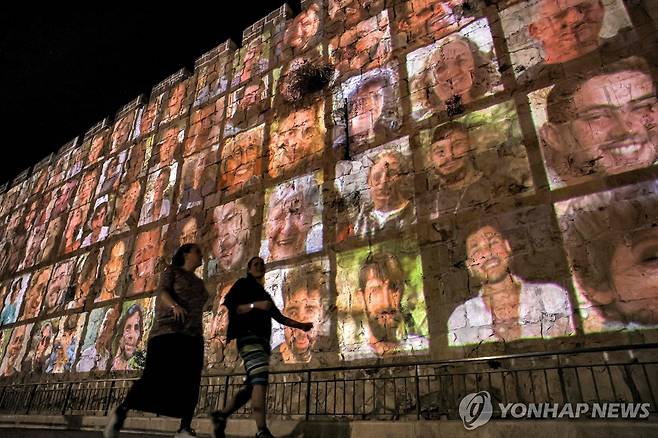 예루살렘 구 시가지 성벽에 띄워진 하마스 인질 사진 (예루살렘 AFP=연합뉴스) 팔레스타인 무장 정파 하마스와 이스라엘 간 무력 충돌이 계속되는 가운데 6일(현지시간) 예루살렘 구 시가지 성벽에 하마스 인질들의 사진이 띄워져 있다. 이날 베냐민 네타냐후 이스라엘 총리는 인질 석방이나 구호품 전달 등을 위해 "전술적 일시 중지"를 검토할 것이라고 말했다. 2023.11.07 ddy04002@yna.co.kr