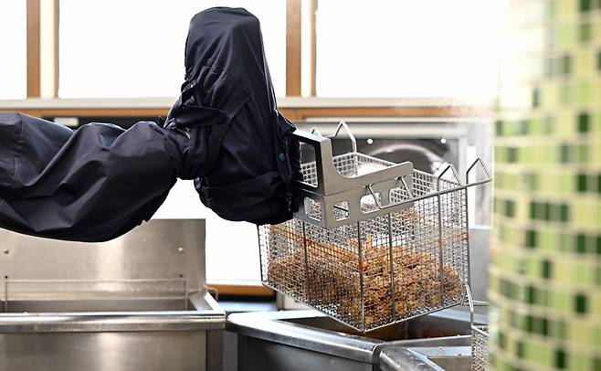 A robot designed to perform culinary tasks prepares school meals for 730 people, including students and school staff members, at Soonggok Middle School in Seongbuk-gu, northern Seoul. (Joint Press Corps)