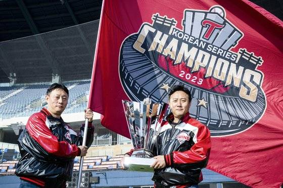 프로야구 LG 트윈스의 ‘쌍둥이’ 직원 김재권 구장관리팀 책임(왼쪽)과 김재환 운영팀 책임. 각각 우승 엠블럼이 든 깃발과 트로피를 들고 잠실구장에서 포즈를 취했다. 장진영 기자