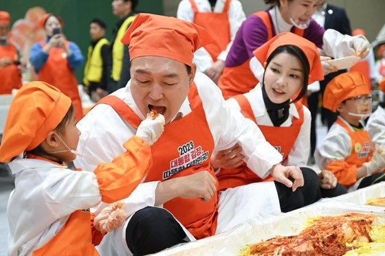 윤석열 대통령이 27일 경기 고양 일산 킨텍스에서 열린 '나눔과 봉사의 국민 대통합 김장행사'에서 어린이와 김치를 시식하고 있다. 사진 대통령실