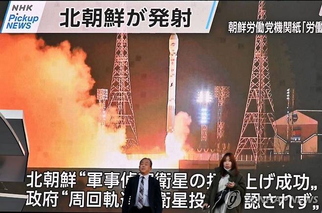 일본 보행자 뒤편에 방송되는 북한 정찰위성 발사 장면 [AFP 연합뉴스 자료사진. 재판매 및 DB 금지]