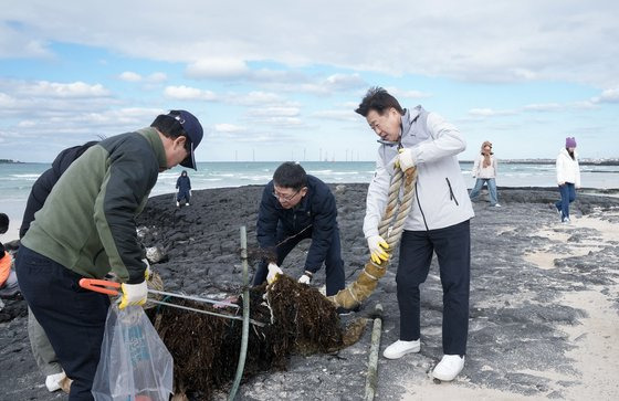 지난 25일 오후 제주 협재해수욕장 일원에서 열린 '제주남방큰돌고래 친구와 함께하는 플로깅'에 참가한 오영훈 제주도지사(오른쪽)가 직원들과 함께 대형 선박용 밧줄 쓰레기를 처리하고 있다. 사진 제주도