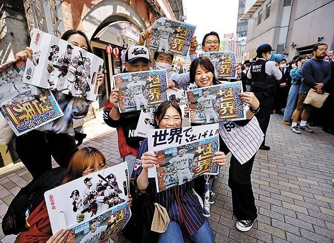 줄서서 받은 WBC 우승 호외 - 도쿄 시민들이 22일 일본 야구대표팀의 WBC 우승 소식을 전한 신문 호외를 들고 즐거워하는 모습. 현지 방송사들이 정규 방송을 중단하고 우승 소식을 보도하는 등 열도 전체가 14년 만의 우승에 열광했다. /로이터 연합뉴스