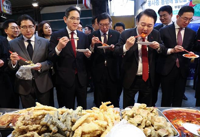 윤석열 대통령이 6일 부산 중구 깡통시장을 방문해 기업인들과 떡볶이를 맛보고 있다. 왼쪽부터 조현준 효성 그룹 회장, 이재용 삼성전자 회장, 박형준 부산시장, 윤 대통령, 구광모 LG그룹 회장. 대통령실통신사진기자단