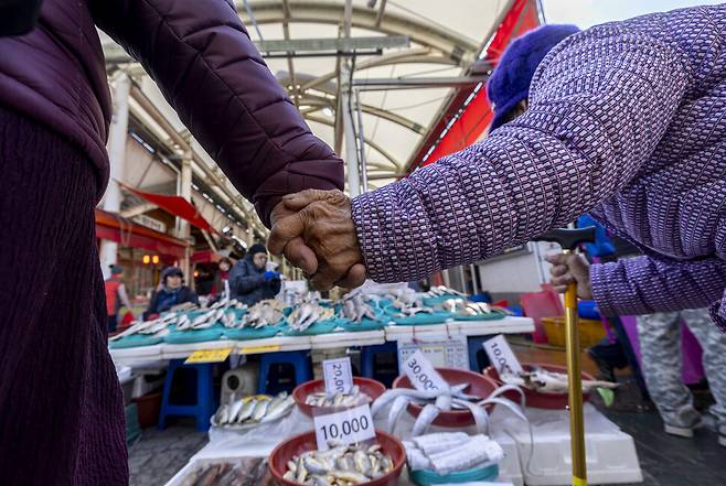 오늘을 넘기면 다시 닷새를 더 기다려야 한다. 장이 선 2023년 11월28일 구례오일장에서 지팡이를 짚은 할머니가 이웃 손을 잡은 채 생선 가게를 돌며 장을 보고 있다.