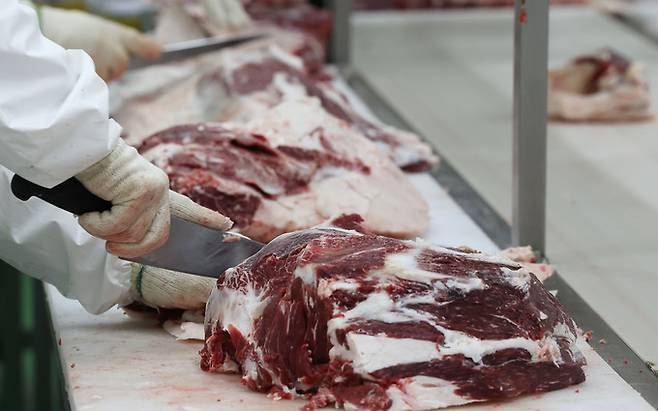 작업자가 부위별로 해체된 한우의 지방을 제거하고 있다.