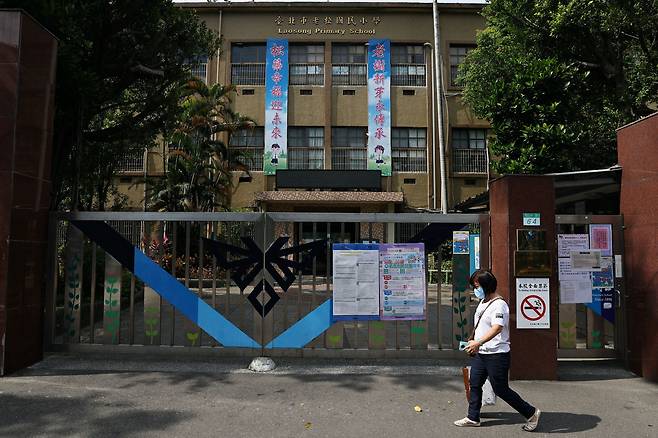 17일 대만 타이베이의 라오송 초등학교 앞을 마스크를 쓴 시민이 지나가고 있다. 대만 정부는 코로나 환자가 급증하자 타이베이, 신베이 등의 초중고에 대해 이달 말까지 등교 중단 조치를 내렸다./로이터 연합뉴스