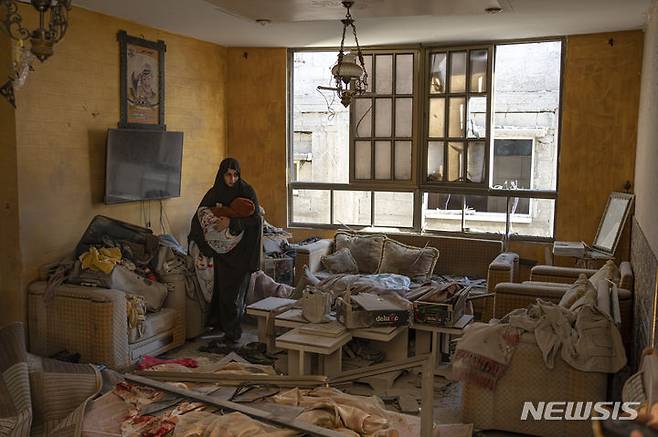 [라파=AP/뉴시스] 가자지구 라파에서 지난 9일(현지시간) 한 팔레스타인 여성이 이스라엘 폭력 영향을 받은 건물에서 아기를 안고 있는 모습. 2023.12.13.