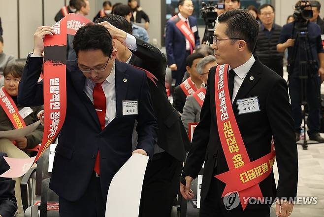 어깨띠 메는 의사들 (서울=연합뉴스) 최재구 기자 = 26일 서울 용산구 대한의사협회에서 열린 의대정원 확대 대응방안 논의를 위한 전국의사대표자 및 확대임원 연석회의에서 이필수 회장과 최대집 전 회장이 어깨띠를 메고 있다. 2023.11.26 jjaeck9@yna.co.kr