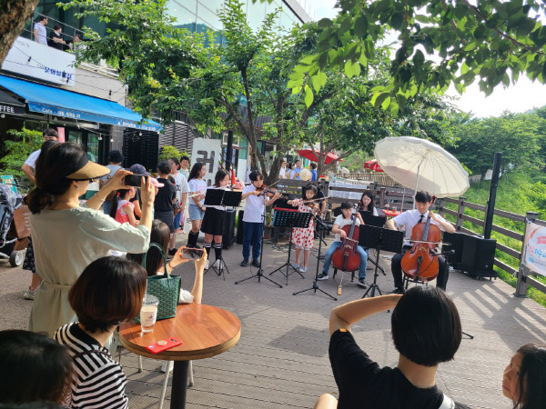 지난 7월 문화예술촌 앞 수변공간에서 클래식 공연이 한창인 가운데 탐방객들이 발걸음을 멈추고 공연을 감상하고 있다.  문화실험실 제공