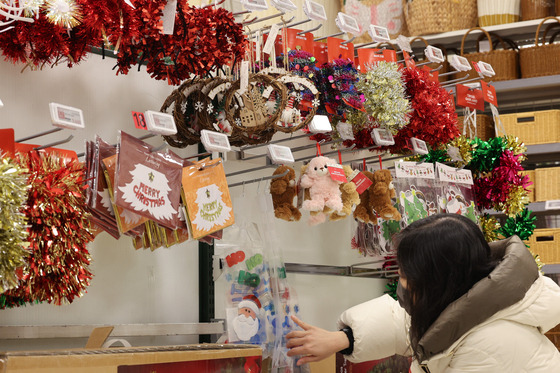 A customer looks at Christmas decorations and party supplies at a supermarket in Seoul on Monday. Social gatherings and festivities are common as the year comes to a close, but as prices rise for drinks and eating out, many people are opting to host gatherings at home. [NEWS1]