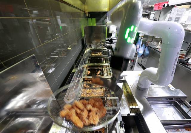 다산동 교촌치킨 점포에서 조리로봇이 튀긴 치킨조각들의 기름을 털고 있다. [교촌에프앤비 제공]