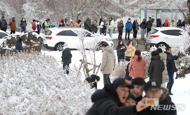 [제주=뉴시스] 우장호 기자 = 주말동안 많은 눈이 내린 가운데 18일 오후 제주 한라산 1100도로 버스 정류장에 설경 감상하고 돌아가려는 방문객들의 줄이 길게 늘어서 있다. 기상청에 따르면 오는 20일부터 이른바 '북극 한파'가 찾아와 올겨울 들어 가장 강력한 추위가 극성을 부릴 것으로 예보됐다. 2023.12.18. woo1223@newsis.com