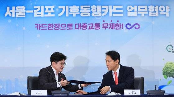 오세훈 서울시장과 김병수 김포시장이 서울-김포 기후동행카드 확대참여 업무협약식에 참석해 협약서에 서명한 뒤 교환하고 있다. [연합뉴스]