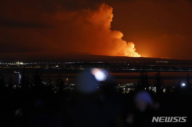 [레이캬비크=AP/뉴시스] 18일(현지시각) 아이슬란드 수도 레이캬비크에서 사람들이 아이슬란드 남서쪽 그린다비크의 화산이 폭발해 연기가 치솟는 모습을 지켜보고 있다. 아이슬란드 당국은 그린다비크 어촌 주민 약 4000명을 대피시키고 인기 관광지인 블루 라군 온천을 폐쇄했다. 2023.12.19.