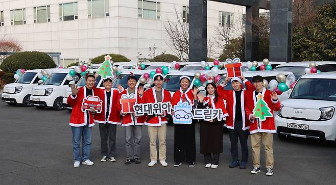 현대위아 직원들이 21일 경남 창원시 본사 앞에서 지역 사회복지기관 20곳에 선물할 ‘현대위아 드림카’와 함께 기념 사진을 찍고 있다. /현대위아 제공