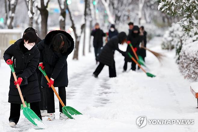 내리는 눈, 치우는 교사들 (광주=연합뉴스) 정다움 기자 = 대설경보가 발효된 21일 오전 광주 서구 치평동 한 인도에서 인근 초등학교 교사들이 제설 작업을 하고 있다. 2023.12.21 daum@yna.co.kr