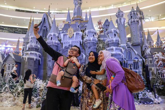 19일 인도네시아 자카르타의 한 쇼핑몰에서 히잡을 쓴 여성을 포함한 무슬림 가족이 크리스마스 장식물을 배경으로 사진을 찍고 있다. 자카르타=EPA 연합뉴스