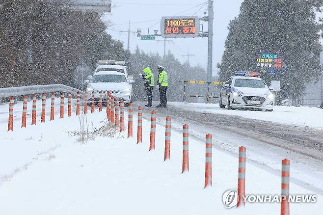 제주 1100도로 통제 (제주=연합뉴스) 박지호 기자 = 폭설이 쏟아진 21일 오후 제주시 노형동 축산진흥원 앞 도로에서 경찰이 1100도로 진입을 통제하고 있다. 2023.12.21 jihopark@yna.co.kr