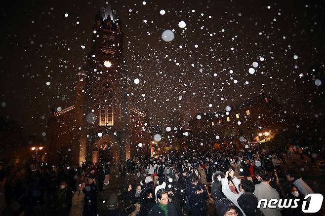 서울을 비롯한 중부지역에 눈이 내리고 있는 25일 새벽 서울 중구 명동성당 앞에서 시민과 관광객이 화이트 크리스마스를 즐기고 있다. 서울은 이번 눈으로 8년만에 화이트 크리스마스다. 2023.12.25/뉴스1 ⓒ News1 박세연 기자