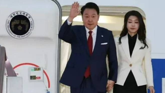 South Korean President Yun Suk-yol and his wife, Kim Gun-hee, raise their hands to greet guests as they disembark from Air Force One on Sept. 11. Yonhap News Agency