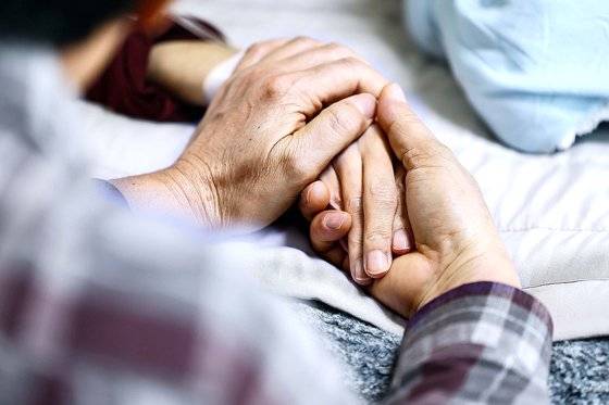 한 보호자가 말기암 환자의 손을 잡아주고 있다. 중앙포토