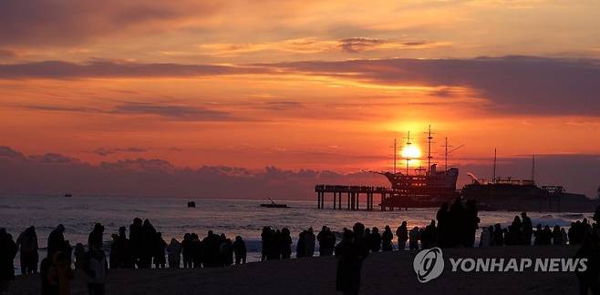 지난 24일 일출 명소인 강원 강릉시 강동면 정동진 해변을 찾은 많은 해맞이 관광객이 일출을 바라보고 있다. 연합뉴스