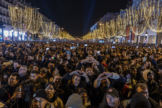 프랑스 파리 샹젤리제 거리에서 시민들이 신년 축하 조명 쇼를 관람하면서 손하트를 날리고 있습니다. AP 연합뉴스