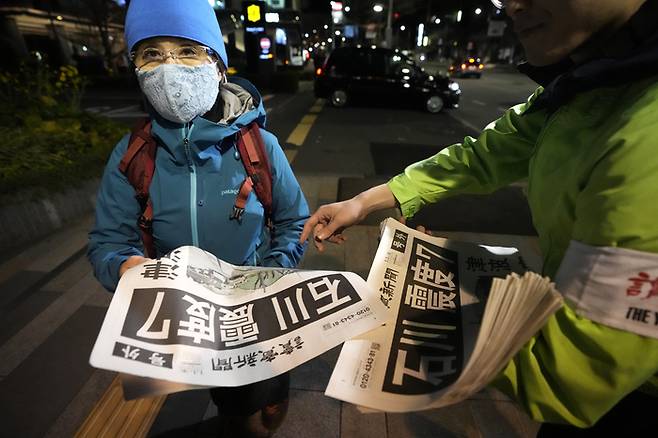 도쿄 시민들이 1일 지진 소식을 보도하는 요미우리 신문 호외를 받아보고 있다. 헤드라인에는 “이시카와, 지진 진도 7”이라고 적혀 있다. [AP연합]