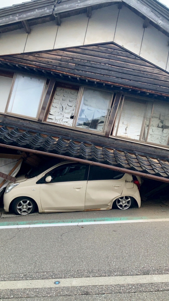1일 일본 강진으로 이시카와현 시카 마을에서 차량이 무너진 건물에 깔려 있는 모습. 로이터 연합뉴스