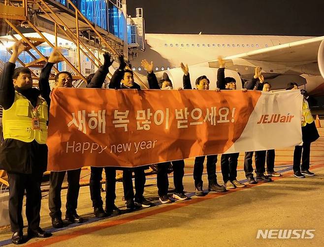 [서울=뉴시스]김이배 제주항공 대표이사(사진 왼쪽에서 여섯번째)와 임직원들이 인천국제공항에서 새해 첫 출발편탑승객들에게 인사를 하고 있다.(사진=제주항공 제공)