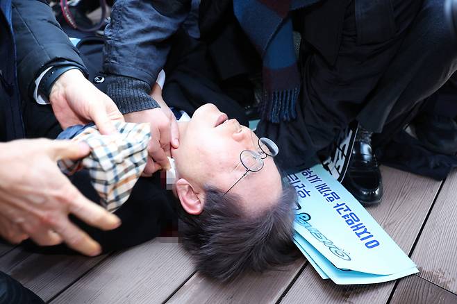 더불어민주당 이재명 대표가 2일 부산 가덕도 신공항 부지를 둘러본 후 기자들과 문답을 진행하던 중 왼쪽 목 부위에 습격을 당해 피를 흘린 채 쓰러져 있다. 연합뉴스