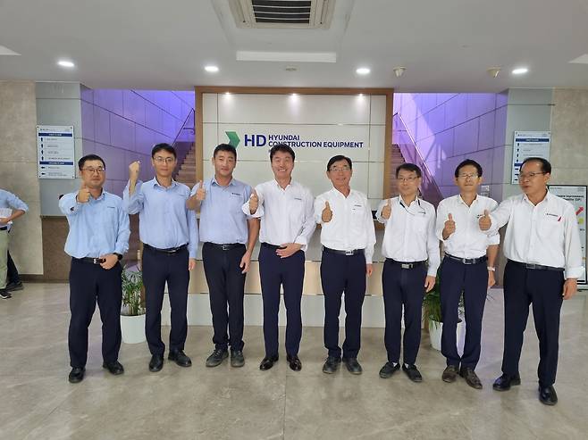 HD현대건설기계 인도법인 주재원들이 본관 1층 CI 앞에서 포즈를 취하고 있다./ 푸네(인도)=박정엽 기자