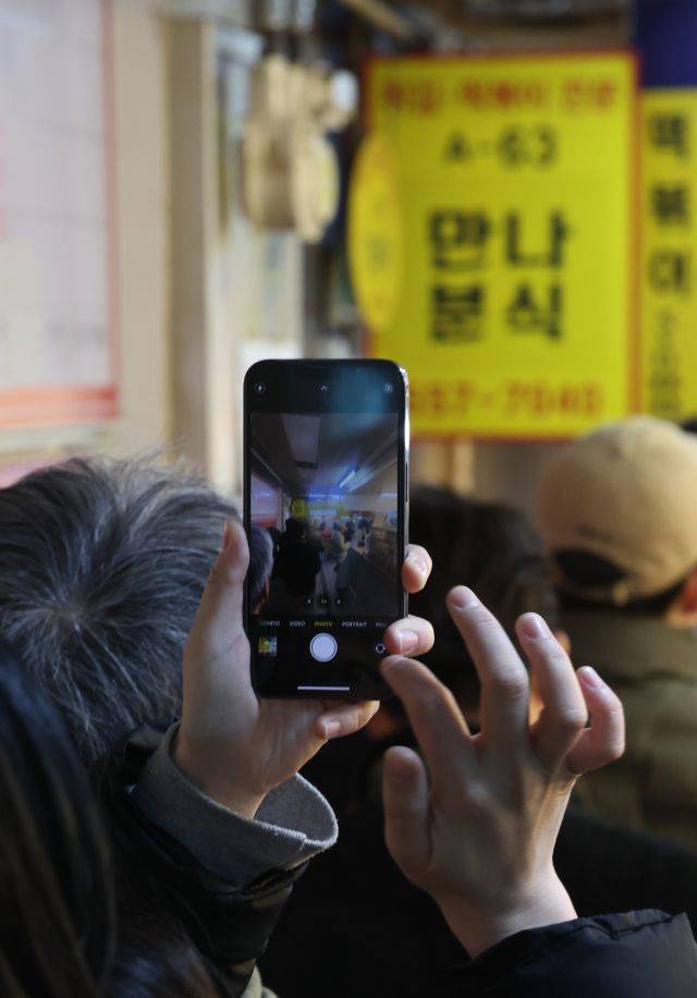 한 시민이 7일 서울 강남구 대치동 은마종합상가에서 30년 넘게 운영된 ‘만나분식’의 마지막 풍경을 스마트폰 카메라에 담고 있다. 이곳은 사장 부부의 건강 악화로 오는 8일 문을 닫는다. 연합뉴스