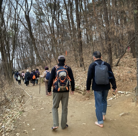 People walk down Daemo mountain barefoot for earthing effects. [KIM JU-YEON]