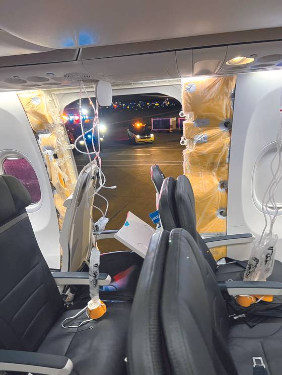 Passenger oxygen masks hang from the roof next to a missing window and a portion of a side wall of an Alaska Airlines Flight 1282, which had been bound for Ontario, California and suffered depressurization soon after departing, in Portland, Oregon, on Friday in this picture obtained from social media. [REUTERS/YONHAP]