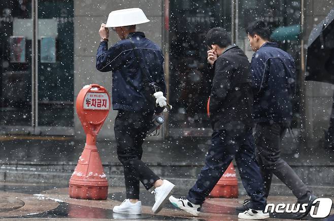 전국에 많은 눈이 내리는 9일 오후 서울 중구 명동 거리에서 한 시민이 바가지를 머리에 쓰고 걷고 있다. 2024.1.9/뉴스1 ⓒ News1 김민지 기자