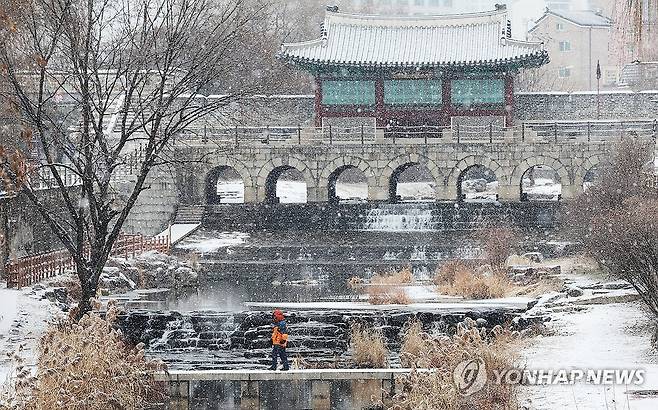 눈 내리는 화홍문 (수원=연합뉴스) 홍기원 기자 = 경기도 전역에 대설주의보가 발효된 9일 오전 경기도 수원시 팔달구 세계문화유산 화성(華城) 화홍문에서 시민이 눈을 맞으며 다리를 건너고 있다. 2024.1.9 xanadu@yna.co.kr